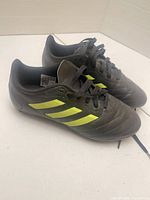 Side view of both cleats showing upper material and neon stripes