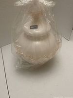 Full view of wrapped opaque white Murano glass covered vase showing pink ruffled edges