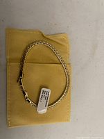 Bracelet with tag on yellow pouch, full view