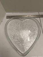 Front view showing heart shape and embossed floral bouquet design with ruler for scale