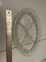 Round clear pressed glass bowl next to ruler showing size and pattern detail