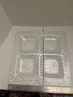 Square clear textured glass platter with four compartments next to ruler