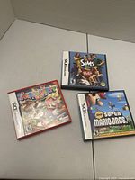Front view of three Nintendo DS cases: Mario Party DS (red), The Sims 2 Pets (black), New Super Mario Bros (black)
