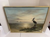 Front view of framed oil painting showing pelican, sunset seascape
