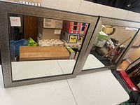 Front view of square wall mirror showing antique silver scroll frame