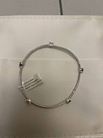 Bracelet laid flat showing beads and five square stones with tag