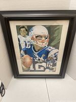 Front view of framed Tom Brady poster under glass in black frame