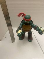 Front view of Raphael figure with ruler for scale