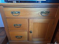 Front view showing three drawers, one door, brass handles