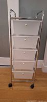 Full view of chrome rolling cart showing five frosted drawers and casters