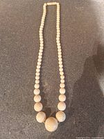 Full view of cream graduated bead necklace laid flat