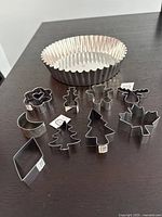 Tart pan with fluted edge and collection of 10 cookie cutters arranged in front