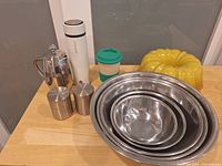 Group shot of bundt pan, mixing bowls, canisters, thermos, travel cup, Bodum press