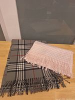 Grey plaid and pink gingham cashmere scarves on table