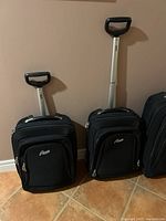 Two carry-on Roots suitcases with telescoping handles extended