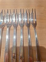 Six three-tine fish forks, handles and tines visible