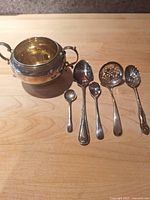 Sugar bowl and five spoons on wooden surface