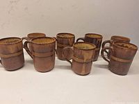 All eight brown drip-glaze pottery mugs