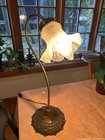 Full view of lamp lit showing brass body and pressed glass shade