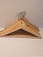 Stack of wooden clothes hangers showing front profiles and hooks