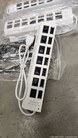White 7-port USB hub showing ports, power switches and attached USB-A cable; additional hubs in background