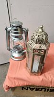 Silver aluminum LED hurricane lantern and brass-plated Moroccan style LED lantern side by side
