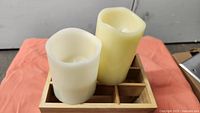 two LED candles sitting on 9-slot wooden box
