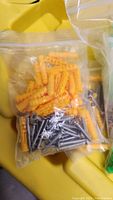 Yellow plastic wall anchors and steel screws in zip bag