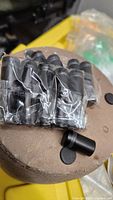 Bundle of black matte cylindrical clamps in plastic wrap with removable rubber pads