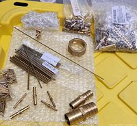 Overview of brass inserts, rods, fittings, hex nut and rod on yellow surface