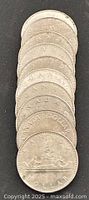 Stack of ten Canadian one-dollar coins showing voyageur canoe reverse