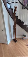 Full view of tall giraffe sculpture beside staircase showing height and base