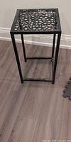 Full view of black metal side table with perforated top