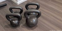 Four CAP cast iron kettlebells grouped on floor, two smaller 15 lb, two larger 35 lb visible