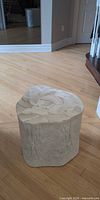 Overall view of off-white faux wood stump stool showing bark texture and top surface