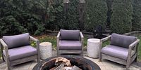 Three armchairs arranged around a fire pit, showing overall style, wood finish and cushion color