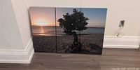 Front view of three-panel beach sunset canvas wall art leaning against wall