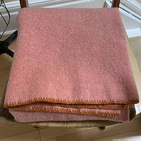 Folded coral wool blanket on chair showing crochet edge