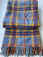 Folded wool plaid blanket showing colour and fringe