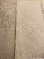 Close view of folded damask cloth showing rose motif and fabric texture