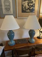 Both ceramic lamps side by side on table with shades