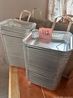 Two tall nested stacks of aluminum trays on tabletop