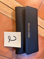 Exterior view of black Michael Kors wallet closed, logo visible