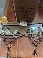 Two gold-tone branch wall hangings with leaves beside open original box