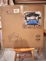 Front of sealed shipping box showing diagram of assembled elevated dog bed with canopy