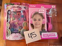 Front view of both sealed items: Petz-Let Series 1 bracelet kit and Vivitar pink headphones