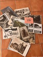Top view of assorted black-and-white postcards with people, places, German flag card, portrait of man in uniform, lot number card