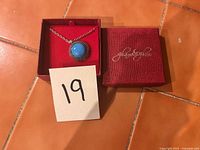 Necklace displayed in open red Glam & Glow box beside matching lid