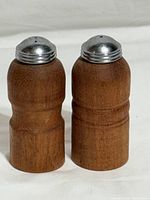 Front view of both teak shakers showing wood grain and metal tops