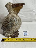 Left side view of ceramic pelican with tape showing length